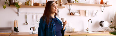 A woman with Waardenburg syndrome smiles while holding a cup in her home kitchen, bannerの写真素材