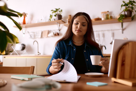 A woman with Waardenburg syndrome works from home, sipping coffee while reviewing documents.の写真素材