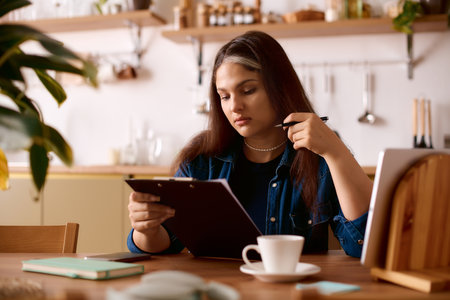 A woman with Waardenburg syndrome focuses on her work while enjoying a warm drink at home.の写真素材