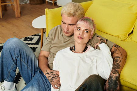 Couple relaxes together on a bright yellow couch, enjoying each others company and warmth.
