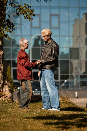 A young couple shares smiles and laughter in a vibrant park under blue skies.の写真素材