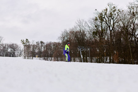 A bearded man enjoys an exhilarating snowboard ride down a snowy slope, surrounded by winter trees.の写真素材