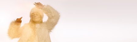 A young blonde woman enjoys winter in a cozy outfit against a soft white background, bannerの写真素材