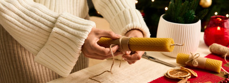 Wrapping handmade candles with natural twine, creating festive decor for a joyful holiday season.の写真素材