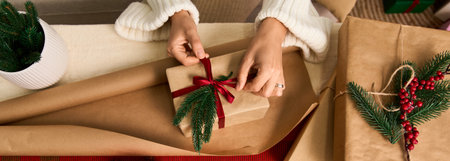 Hands carefully wrap a beautifully decorated gift with festive touches for Christmas joy.