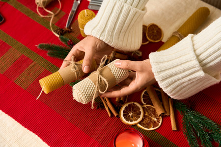 Hands arrange natural decor beeswax candles, dried fruits, and spices for Christmas.の写真素材