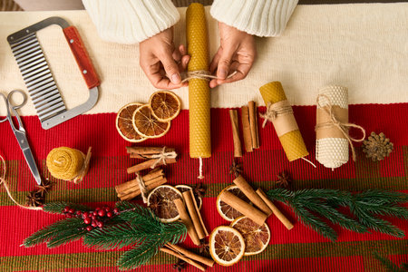Hands create beautiful candles with natural decor, celebrating the joy of the holiday season.の写真素材