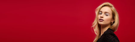 A young blonde woman models a stylish black evening outfit on a festive red background, bannerの写真素材
