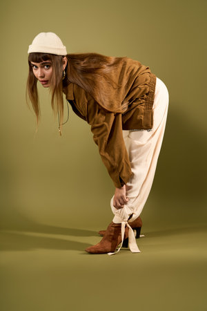 A beautiful young woman adjusts her stylish outfit, embodying fashion creativity and confidence.の写真素材