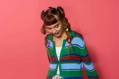 Young woman with colorful accessories smiles lightly, showcasing her trendy outfit and hairstyle.の写真素材