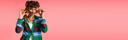 A young, pretty woman with a stylish outfit playfully holds her sunglasses while posing.の写真素材