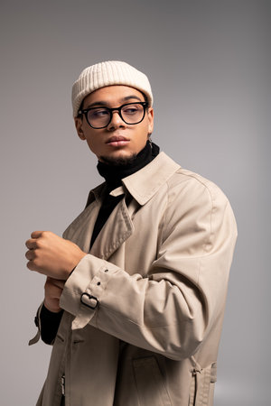 Young man poses confidently in a fashionable outfit, exuding charm and style effortlessly.の写真素材