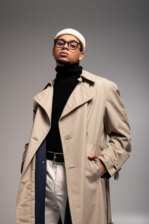 Handsome young man displays his fashionable attire with confidence in a sleek, trendy space.の写真素材