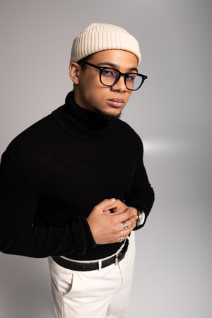 Young man confidently posing in trendy attire against a simple backdrop.の写真素材