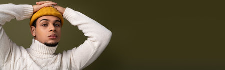 Handsome young man in a chic outfit strikes a confident pose against a neutral backdrop.の写真素材