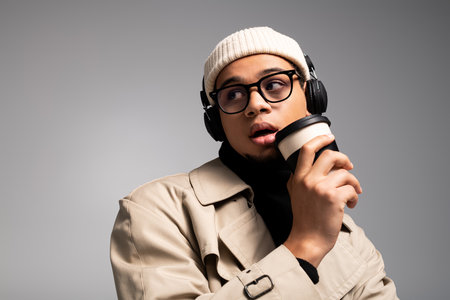 A stylish young man sips coffee and enjoys music, effortlessly blending fashion and relaxation.の写真素材