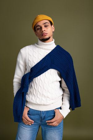Fashionable young man poses confidently in a cozy sweater and stylish beanie, exuding charm.の写真素材