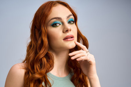 A redhead woman showcases stunning makeup while posing in a clean studio background.の写真素材