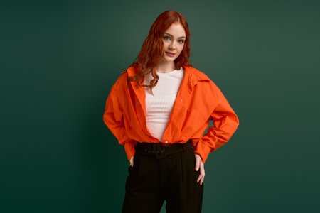 A redhead woman wears an orange shirt against a lush green background, embodying autumn style.の写真素材