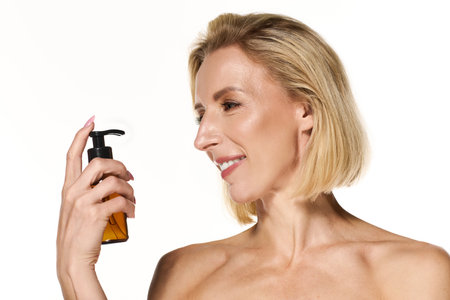 A beautiful blonde woman smiles while holding a skin care product.