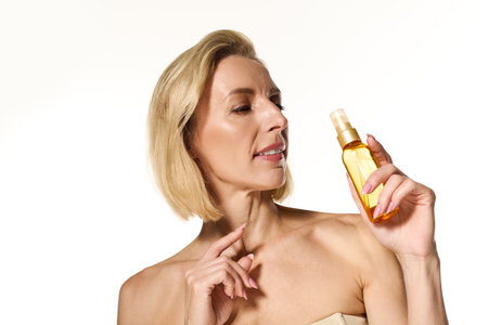 A stylish blonde woman with short hair promotes a skincare product, exuding elegance.の写真素材