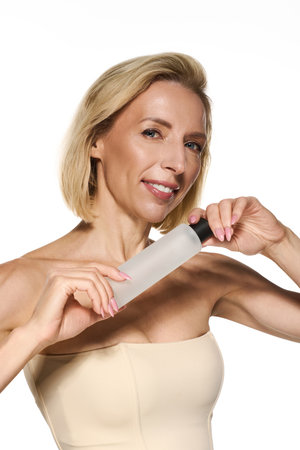 A blonde woman with short hair showcases a skin care product, radiating beauty and health.の写真素材