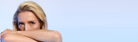 A stylish blonde woman with short hair poses elegantly in chic black attire, bannerの写真素材