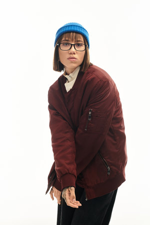 A stylish young woman poses confidently, displaying her unique fashion sense in a minimalist studio.