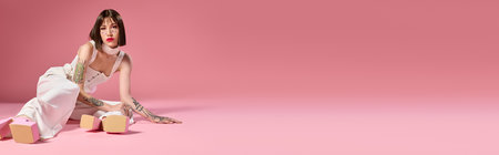 A beautiful young woman poses in fashionable attire against a striking pink backdrop.の写真素材