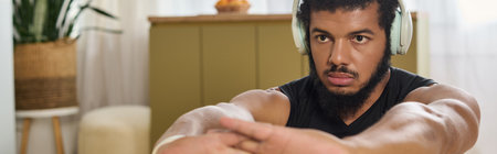 An athletic man performs his workout routine at home, focusing intensely on his movements and music,...