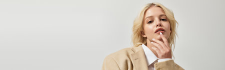 A beautiful young blonde woman showcases winter fashion trends in a sleek  white studio, bannerの写真素材