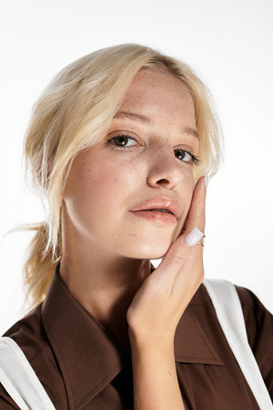 A beautiful young woman in trendy winter attire poses elegantly in a bright studio.の写真素材