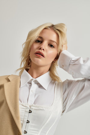 A beautiful young blonde poses confidently in a trendy winter outfit, radiating style.の写真素材