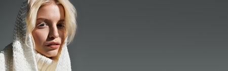 A young blonde woman with white eyelashes poses in a cozy scarf, bannerの写真素材