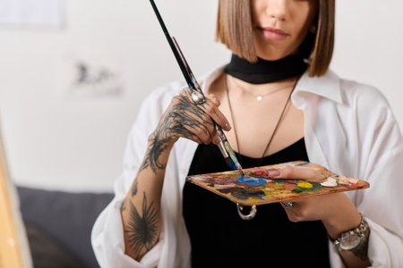 Young artist mixes colors on a palette, focusing on her canvas at home.の写真素材