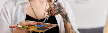 A young woman expresses her creativity while painting at home with vibrant colors in hand.の写真素材