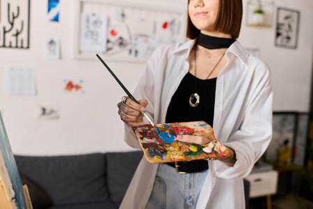 Young woman at home joyfully painting on a canvas, showcasing her creative talent and passion.の写真素材