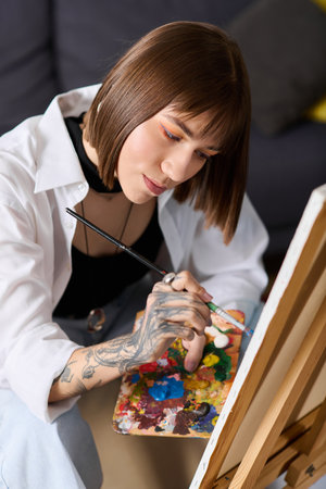 Young woman engaged in painting, showcasing her creativity in a comfortable home environmentの写真素材