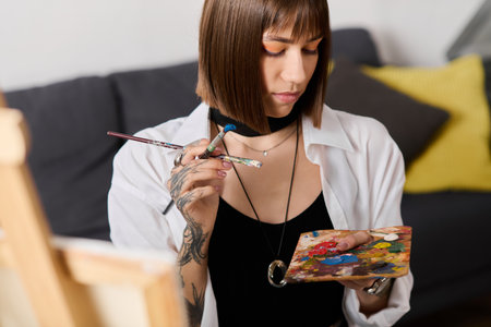Young woman engages in painting at home, experimenting with vibrant colors on a palette.の写真素材