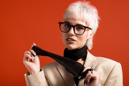 A young, beautiful woman with short hair and glasses displays confidence while holding a scarf.の写真素材