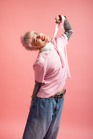 A young woman beams in a playful outfit, posing joyfully in a bright setting.の写真素材