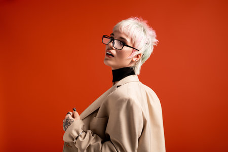 A confident young woman flaunts her unique style in a trendy outfit and glasses.の写真素材