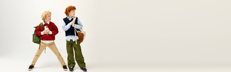 Two fashionable boys stand with backpacks, excited and ready for school, showcasing youthful joy.