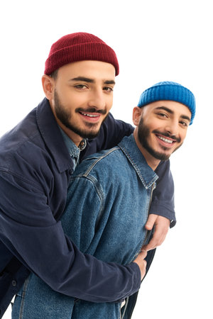 Two handsome brothers dressed in fashionable outfits embrace each other, radiating joy and style.の写真素材