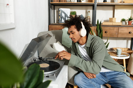Young handsome man listens to vinyl records in his comfortable, stylish living space.の写真素材