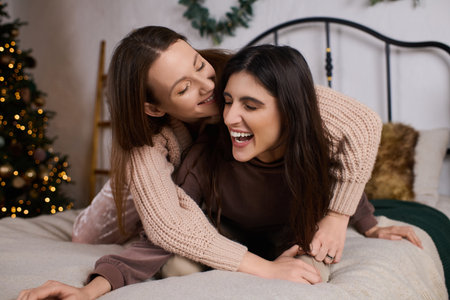 Two beautiful women share warm moments together in cozy attire, celebrating their love in winter.の写真素材