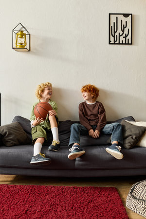 Two happy boys laugh and play together with a basketball in a stylish home setting.の写真素材