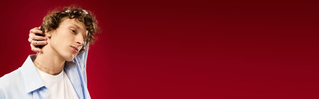 Handsome young man poses confidently in trendy outfit with a striking red background.の写真素材