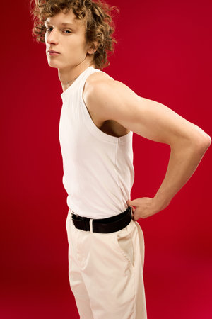 Handsome young man showcases a modern fashion sense with a striking red background.の写真素材