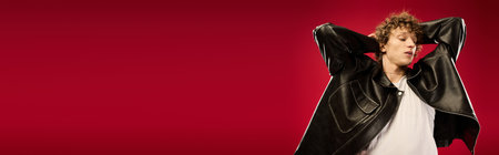 Young man poses stylishly, exuding charm and confidence with a striking background.の写真素材